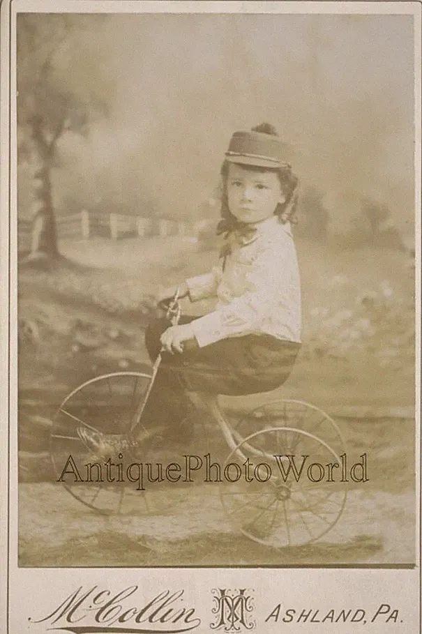Cute boy on iron tricycle bicycle antique cabinet photo